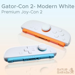 May include: Two white Gator-Con 2 Joy-Con controllers with orange and blue accents. The controllers have white buttons and joysticks. The text "Gator-Con 2 - Modern White Premium Joy-Con 2" is at the top of the image. The Gator Garage logo is at the bottom.