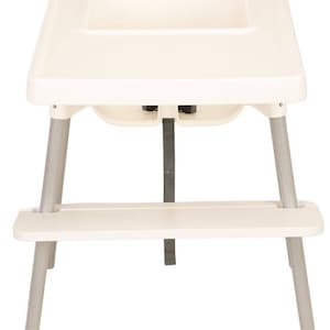 Op de afbeelding: Een witte plastic hoge stoel met een dienblad en een veiligheidsriem. De stoel heeft een wit metalen frame en een voetensteun.