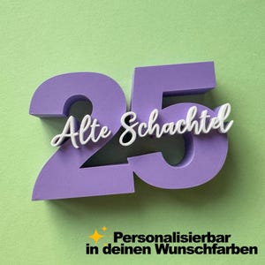 Könnte beinhalten: Eine dreidimensionale violette Zahl 25 mit dem weißen, in Schreibschrift gehaltenen Text Alte Schachtel auf der Vorderseite. Darunter steht der schwarze Text Personalisierbar in deinen Wunschfarben neben einem kleinen gelben Sternsymbol.