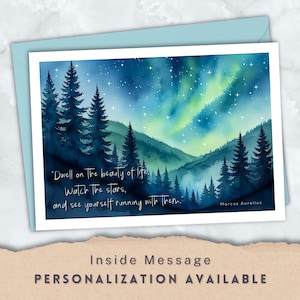 May include: A greeting card featuring a watercolor painting of a night sky with the aurora borealis and pine trees. The card includes a quote by Marcus Aurelius: "Dwell on the beauty of life, Watch the stars, and see yourself running with them."