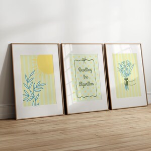 May include: Three framed art prints with a light wood frame. The prints feature illustrations of a sun, a plant, a bouquet of flowers, and the text "Resetting the Algorithm" on a yellow and white striped background.