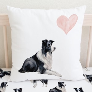 May include: A white crib sheet with a black and white border collie dog print. A white pillow with a pink heart and a black and white border collie dog is on top of the sheet.