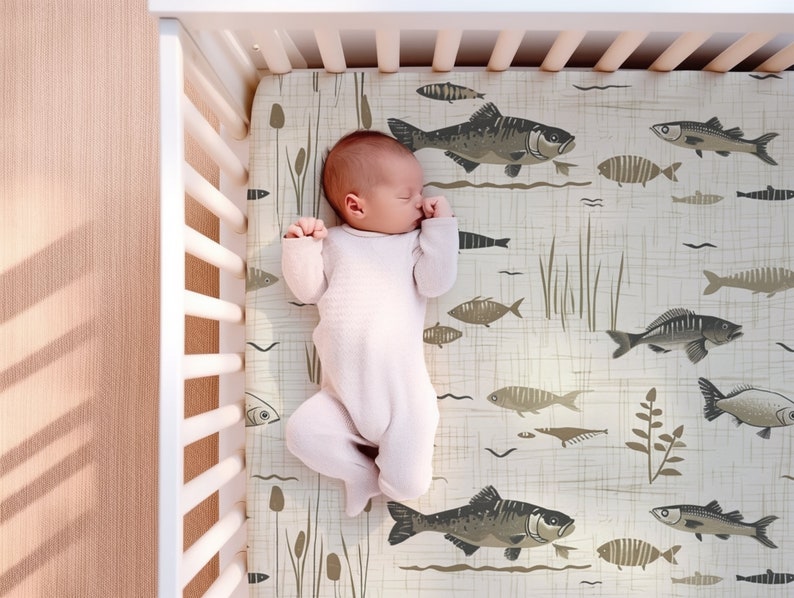 May include: A baby sleeping in a crib with a white crib sheet featuring a brown and white fish pattern.