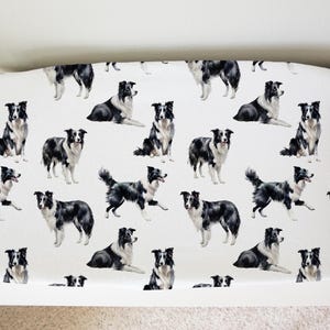 May include: White fabric with a repeating pattern of black and white border collie dogs. The dogs are in various poses, including sitting, standing, and running.