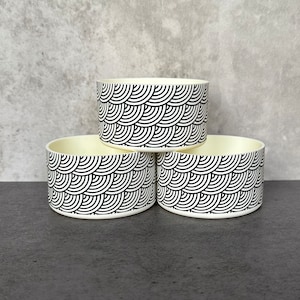 May include: Three white bowls with a black and white geometric pattern. The bowls are stacked on top of each other.