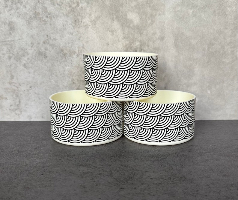May include: Three white bowls with a black and white geometric pattern. The bowls are stacked on top of each other.