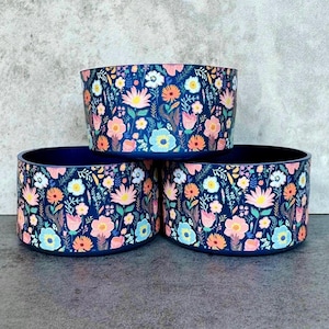 May include: Three blue ceramic bowls with a floral pattern. The bowls are stacked on top of each other. The pattern features pink, orange, yellow, and white flowers on a dark blue background.