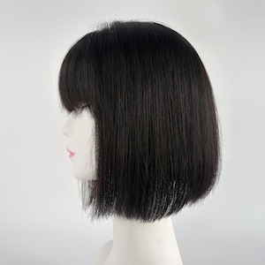 May include: A side profile of a mannequin head wearing a black wig. The wig features a blunt cut with bangs that reach the eyebrows. The hair is straight and falls to the chin.