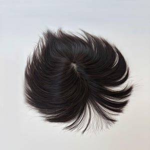 May include: A dark brown hair topper with a central parting. The hair is styled with a natural wave and a slightly tousled appearance. The hairpiece is designed to add volume and coverage.