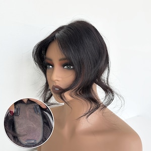 Puede incluir: Un postizo de cabello castaño oscuro con capas onduladas. El postizo se muestra en una cabeza de maniquí. El postizo tiene clips para una fijación segura. El cabello está peinado con una raya lateral.
