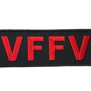 May include: A rectangular black embroidered patch featuring the red text VFFV in a bold, sans-serif font. The patch has a black stitched border and a textured fabric surface, designed for attachment to clothing or other textile items.