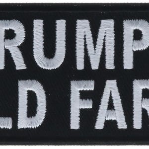 May include: A rectangular black embroidered patch with rounded corners featuring the white stitched text GRUMPY OLD FART in two lines. The lettering is in a bold, sans-serif font style, and the entire patch has a thick black border.