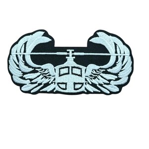 May include: An embroidered patch featuring a white helicopter icon centered between two symmetrical white wings on a black background. The helicopter design includes a rotor blade extending horizontally across the top of the wings.