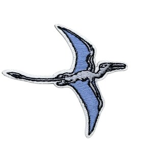 May include: An embroidered patch featuring a flying pterosaur in profile. The creature has light blue wings with dark blue outlines, a white body, and a long, thin tail. The entire design is bordered by a white stitched edge on a plain background.