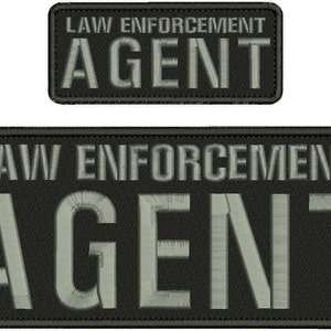 Könnte beinhalten: Zwei rechteckige gestickte Aufnäher mit schwarzem Stoffhintergrund und grauer Stickschrift. Der Text auf beiden Aufnähern lautet LAW ENFORCEMENT AGENT in einer fetten serifenlosen Schrift. Die Aufnäher haben einen sauber gestickten Rand.