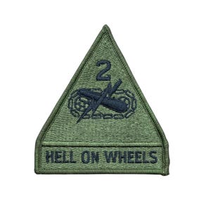May include: A triangular olive green embroidered patch featuring a black number 2 above a black tank track and lightning bolt symbol. Below this, a horizontal bar contains the black text HELL ON WHEELS in a bold, sans-serif font.