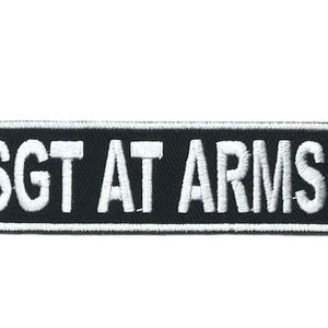 May include: A rectangular embroidered patch with a black background and a white border. The text SGT AT ARMS is stitched in bold white capital letters across the center of the patch. The design features a clean, high-contrast aesthetic.