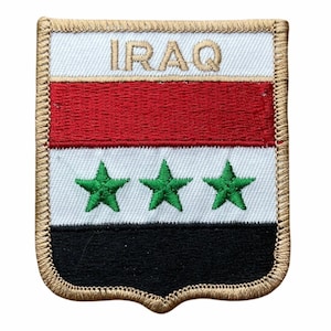May include: A rectangular embroidered patch with a shield-shaped bottom edge, featuring the flag of Iraq with horizontal red, white, and black stripes. Three green stars are centered on the white stripe, and the word IRAQ is stitched in gold.