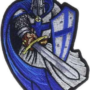 May include: An embroidered patch featuring a knight in silver armor with a blue cape and tunic. The knight holds a silver sword with a gold hilt and a shield decorated with a blue cross. The design is outlined in black thread on a white background.