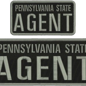 May include: Two rectangular embroidered patches with black fabric backgrounds and grey borders. The text PENNSYLVANIA STATE is embroidered in grey on the top line, with the word AGENT in large grey capital letters on the bottom line of each patch.