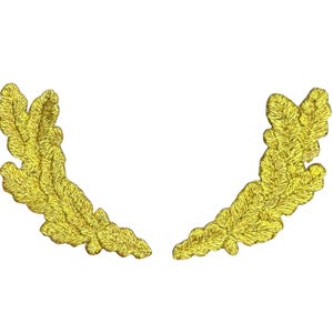 May include: A pair of symmetrical, gold-colored embroidered patches shaped like curved oak leaf branches. Each patch features detailed, raised stitching that mimics the texture and lobed edges of natural oak leaves in a bright, metallic yellow thread.