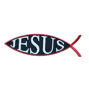 May include: A fish-shaped embroidered patch featuring a dark navy blue background with a thin red border. The word JESUS is stitched in white capital letters across the center of the fish shape, following the curve of the design.
