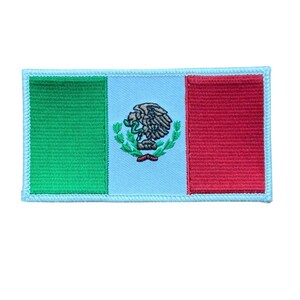 May include: A rectangular embroidered patch featuring a vertical tricolor design of green, light blue, and red. The central light blue section displays a detailed embroidered emblem of an eagle perched on a cactus, clutching a snake.