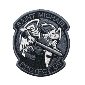 May include: A circular embroidered patch featuring a black and white depiction of Saint Michael holding a sword. The text SAINT MICHAEL is arched across the top, and the text PROTECT US is arched across the bottom, all set against a dark background.