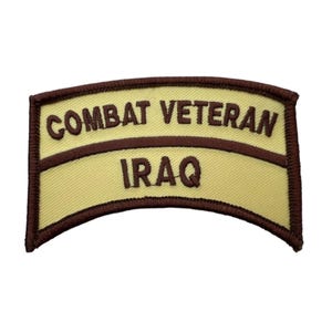 May include: A curved, rectangular embroidered patch with a light tan background and dark brown border. The text COMBAT VETERAN is stitched in dark brown on the top section, and the word IRAQ is stitched in dark brown on the bottom section.