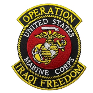 May include: A circular embroidered patch featuring the United States Marine Corps emblem in red, gold, and white. The text reads OPERATION IRAQI FREEDOM and UNITED STATES MARINE CORPS. The design includes an eagle, globe, and anchor on a red background.