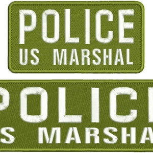 Pode incluir: Dois emblemas retangulares bordados em verde-oliva com cantos arredondados. Cada emblema apresenta a palavra POLICE em letras maiúsculas brancas grandes na linha superior e as palavras US MARSHAL em letras brancas menores na linha inferior.