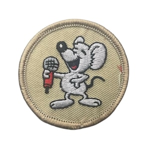 May include: A circular embroidered patch featuring a light gray mouse character holding a red and gray microphone. The mouse has a black nose, a wide smile, and large ears. The background of the patch is tan with a matching tan stitched border.