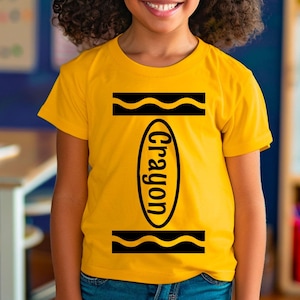 May include: A yellow t-shirt with a black crayon design on the front. The design includes the word "crayon" written vertically inside an oval shape.