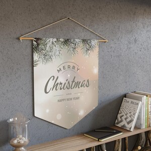 May include: A white banner with a wintery design and the text "Merry Christmas and Happy New Year!" hanging on a wall with a wooden dowel rod.