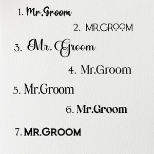 May include: A white card with seven different variations of the text "Mr. Groom" written in black ink. The text is written in different fonts and sizes.