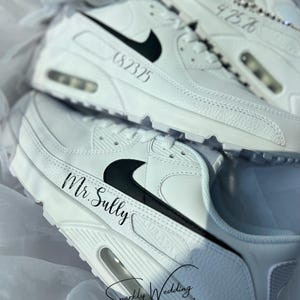 May include: White sneakers with black swoosh logos and personalized text. One pair reads "Mr. Sully" and another displays the date "6.8.2325". The shoes are part of a wedding theme, with the text "Sparkly Wedding Co."
