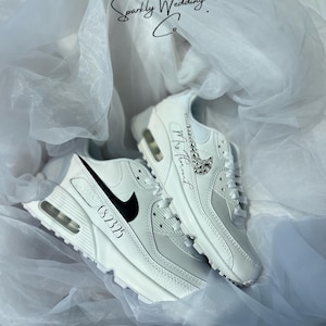 May include: White sneakers with black accents and a black swoosh logo. One shoe has the number "08.23.25" printed on the side, and the other has the text "Mrs. [Name]" with a decorative embellishment. The text "Sparkly Wedding Co." is also visible.
