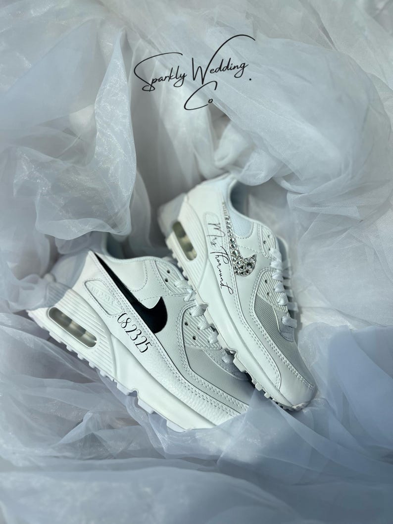 May include: White sneakers with black accents and a black swoosh logo. One shoe has the number "08.23.25" printed on the side, and the other has the text "Mrs. [Name]" with a decorative embellishment. The text "Sparkly Wedding Co." is also visible.