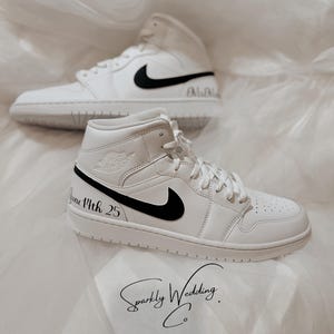 May include: White high-top sneakers with black Nike swoosh and black text that reads "June 14th 25".