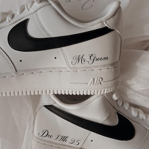 May include: White leather sneakers with black Nike swoosh and black text that says "Mr. Groom" on one shoe and "Dec 17th 95" on the other shoe.