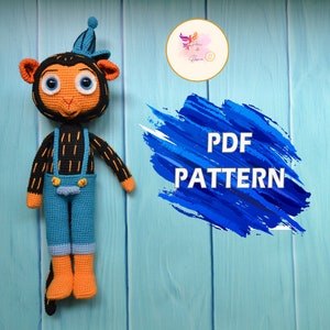 May include: Crochet pattern for a cute monkey wearing overalls. The pattern is available as a PDF download. The monkey is orange, black, and blue.