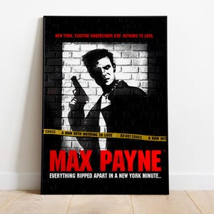以下が含まれることがあります： ビデオゲームMax Payneの額入りポスター。ポスターには、レンガの壁の前で銃を持っている男性の白黒画像が描かれています。「MAX PAYNE」のタイトルは赤色で、タイトルの上と下にテキストがあります。