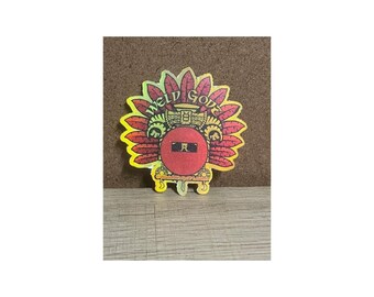 May include: A colorful sticker featuring a Native American headdress design with the words "WELD GODS" in a circular pattern. The sticker has a red and yellow color scheme with a gold base.