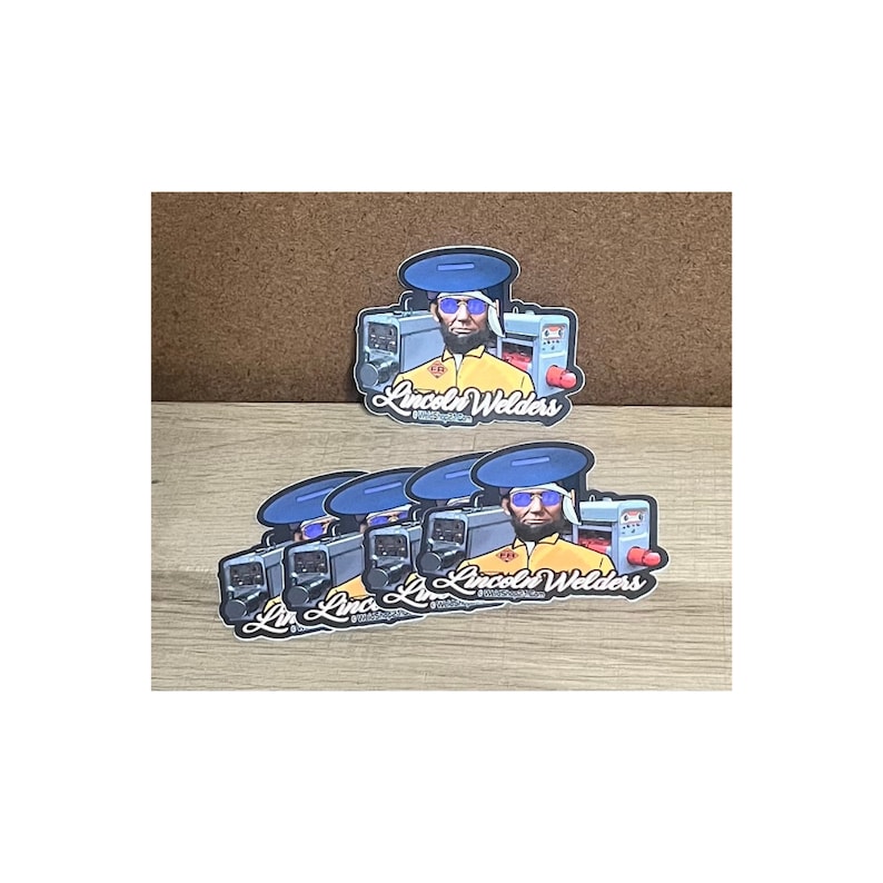 May include: Five stickers featuring a cartoon illustration of a person wearing a blue hard hat and sunglasses, holding a welding machine. The stickers have the text "Lincoln Welders" in a stylized font.