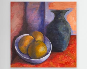 Quiet still life with three oranges in a simple white bowl beside a deep blue vase. Warm, muted tones and bright fruit create a calm balance