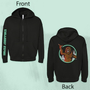 May include: Black zippered hoodie with a graphic print of a red monster on the back. The monster is holding a knife and standing in front of a city skyline. The left sleeve has the text "Uncle Chupters" printed on it.