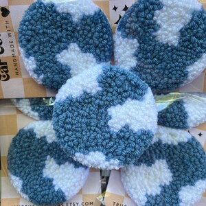 Puede incluir: Cinco círculos de crochet azul y blanco con un patrón de nubes. Los círculos son hechos a mano y tienen una textura esponjosa. El texto "Trucrucreations.etsy.com" es visible en la parte inferior de la imagen.