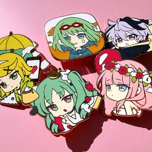 Può includere: Una collezione di cinque spille smaltate colorate raffiguranti personaggi in stile anime. Le spille presentano vari personaggi con acconciature, abiti e accessori distintivi, tra cui un ombrello giallo, una corona e dettagli floreali. Su sfondo rosa.