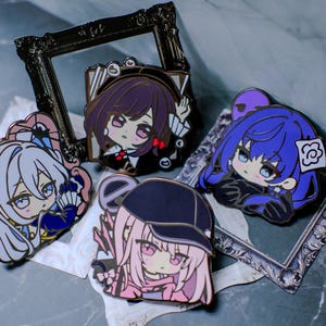 May include: A collection of colorful enamel pins featuring anime-style characters. The pins showcase various characters with detailed designs, including different hairstyles and outfits. The pins are set against a decorative background.