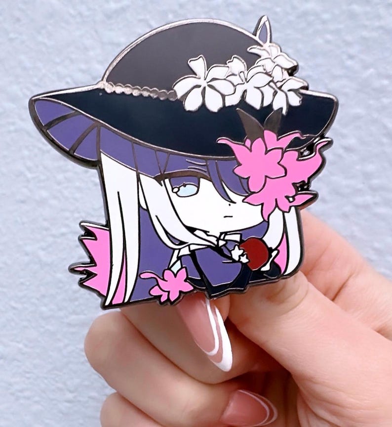 May include: Enamel pin depicting an anime-style character with long white hair, a black hat decorated with white flowers, and pink floral details. The character holds a red apple. The pin has a purple and black colour scheme.